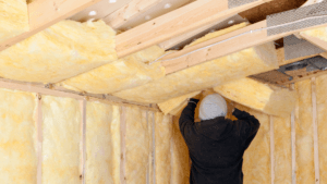 Worker Installing Fiberglass Batt Insulation between Roof Trusses