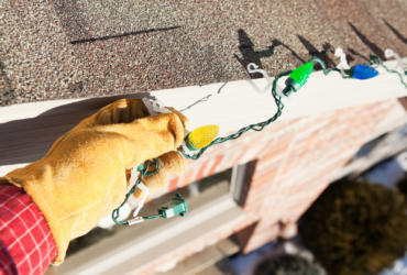 Hand Installing LED Christmas Lights on House Roof