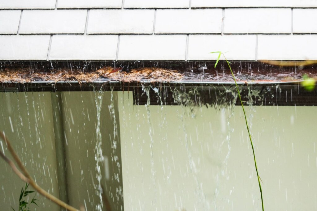 Close up view on clogged Rain Gutter in the rain Home Guttering Gutters1-min