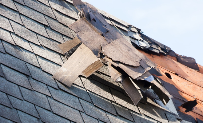 wind storm roofing Huntsville with lifted shingle tabs visible on pitched roof